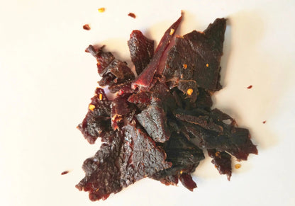 Dried flavored Mango Habanero beef jerky pieces on a white surface