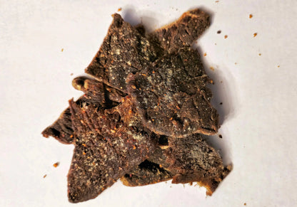 Dried flavored Ginger Lime Whiskey beef jerky pieces on a white surface