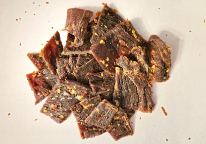 Dried Sweet SrirHOTcha flavored beef jerky pieces on a white surface