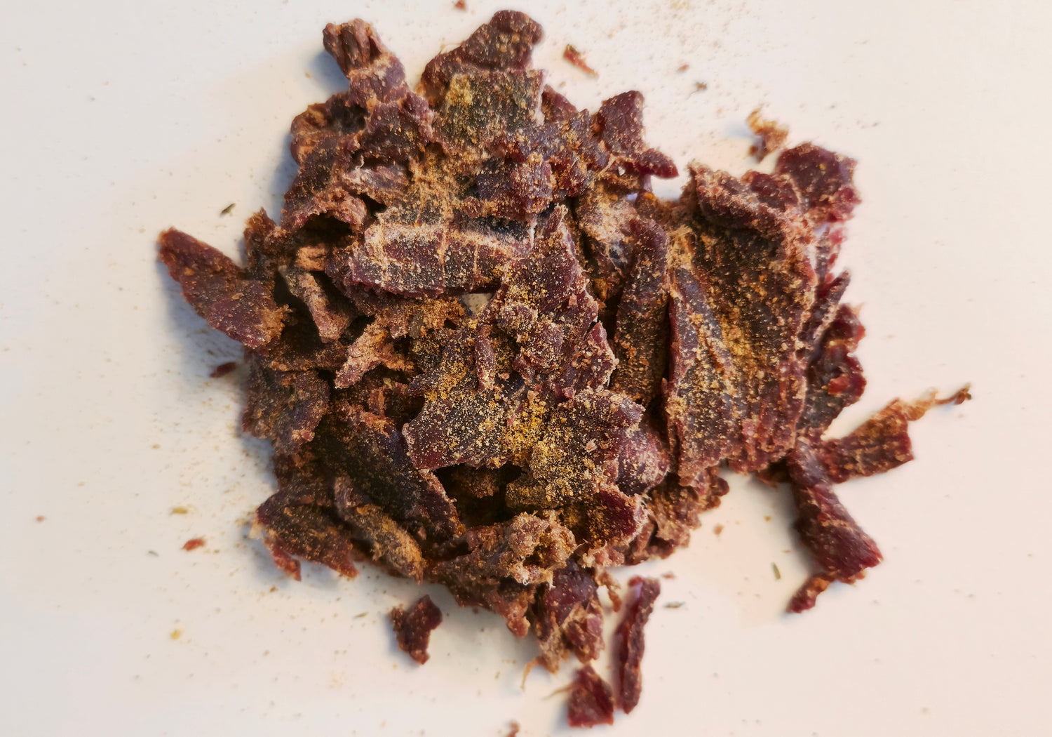 Dried beef jerky pieces on a white surface